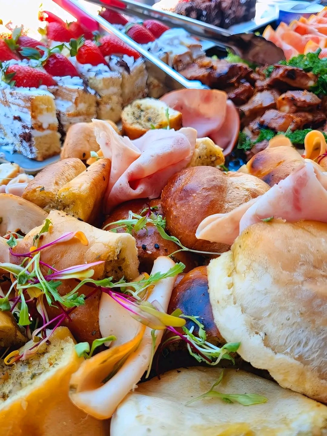 Canapé board with sausage rolls, ham, scones and strawberry cake
