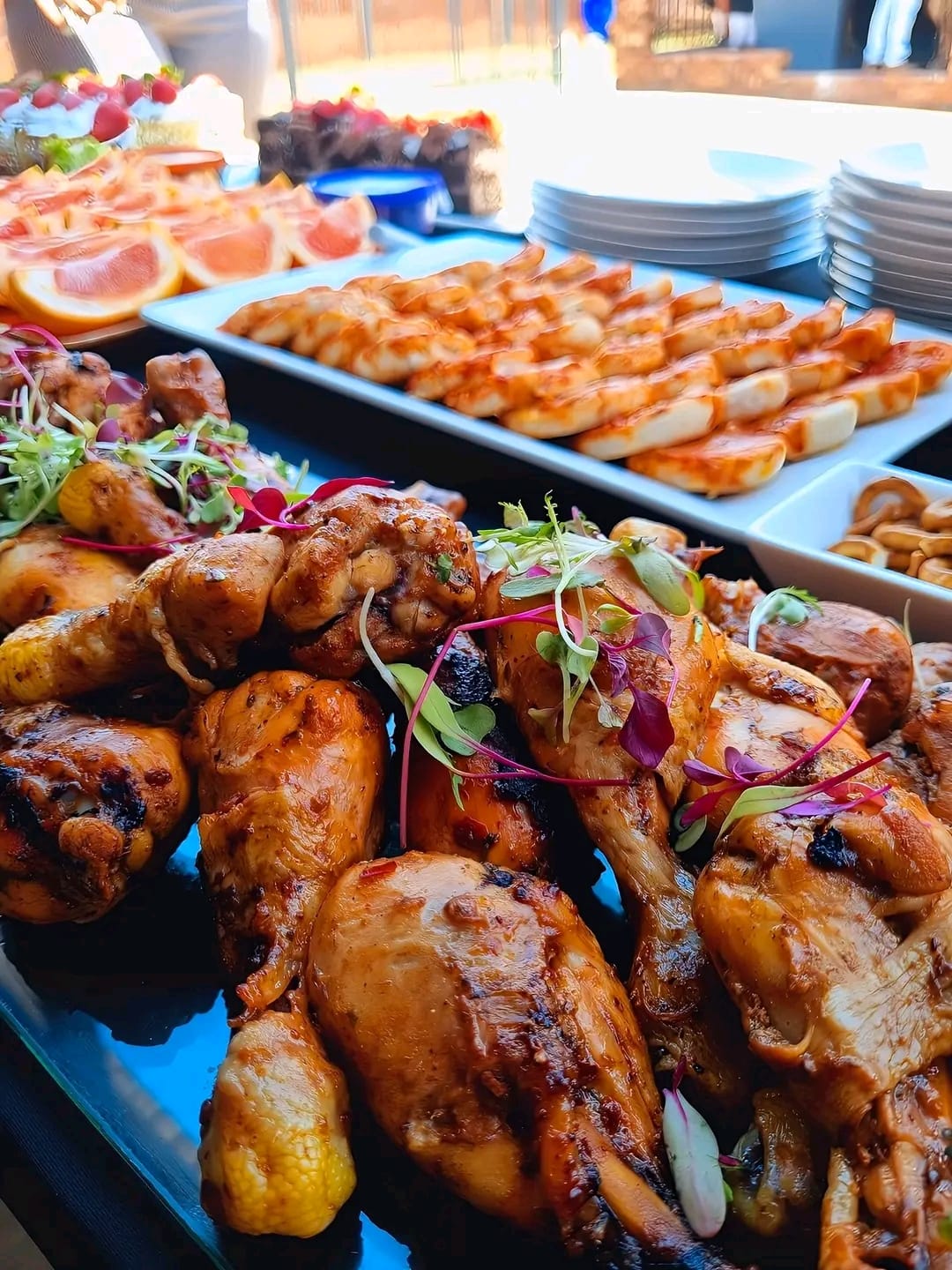 Full buffet spread with glazed chicken drumsticks, rolls and fruit