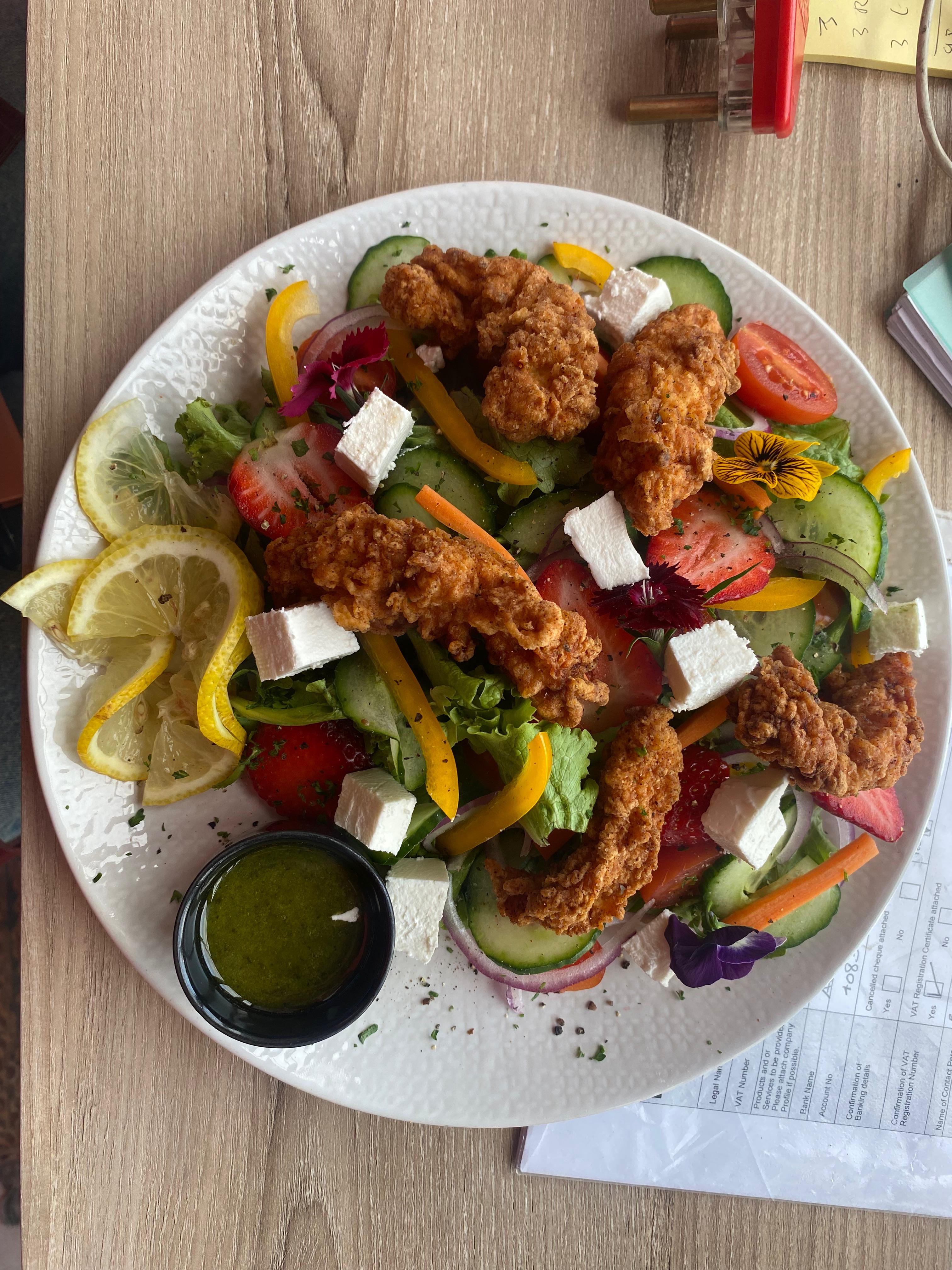 Crispy fried chicken on garden salad with feta and pesto