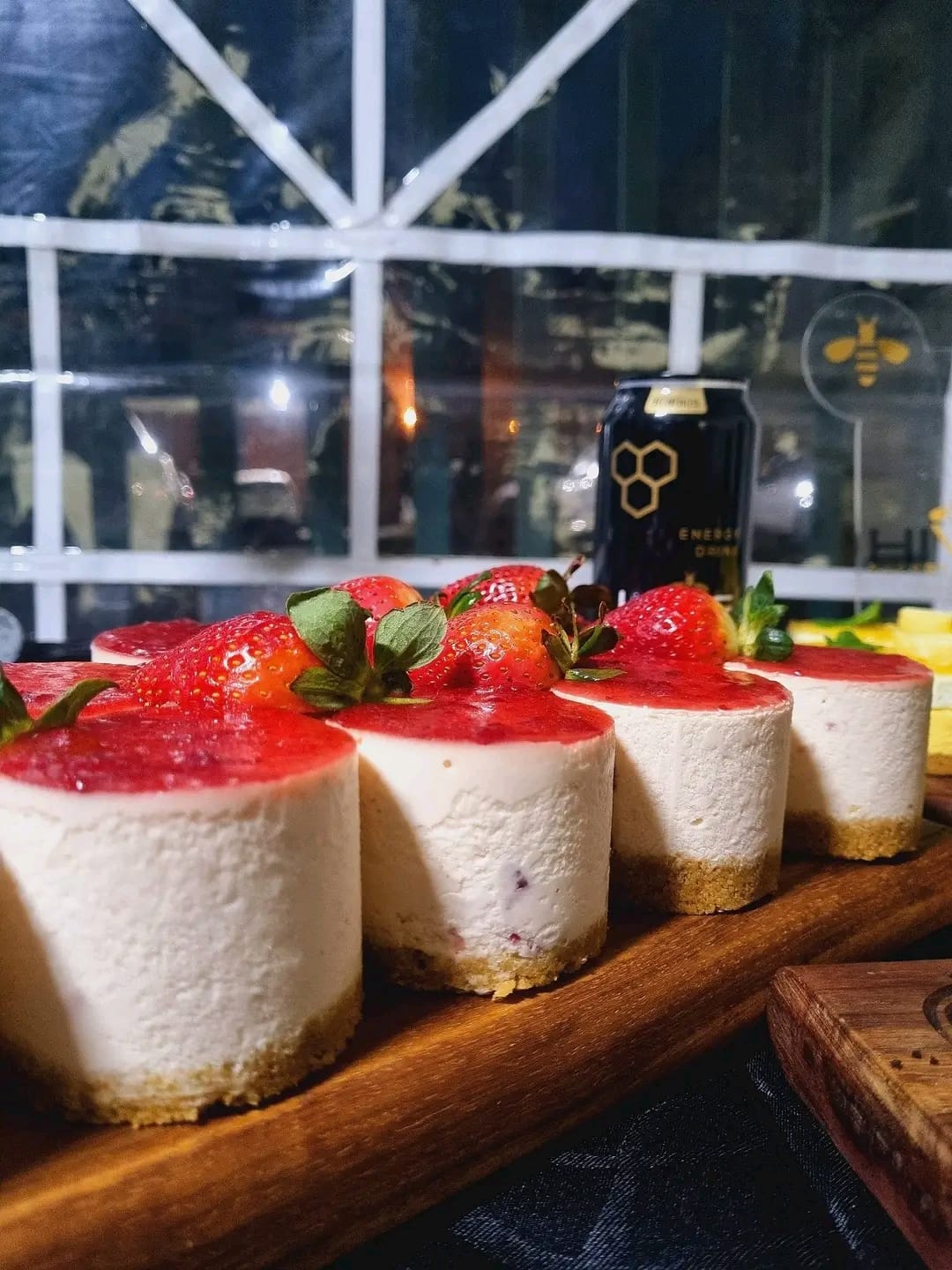 Strawberry cheesecakes with berry glaze on wooden board, dramatic dark setting